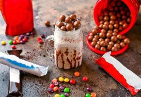 sortiert Schokolade Milchshake mit Eis Creme, bunt bunt Süßigkeiten und ausgepeitscht Sahne serviert im Krug isoliert auf dunkel Hintergrund Seite Aussicht von gesund trinken foto