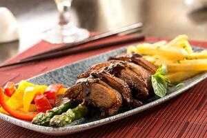 knusprig Ente braten mit Fritten, Tomate und Essstäbchen serviert im Gericht isoliert auf Hintergrund oben Aussicht von Chinesisch Essen foto