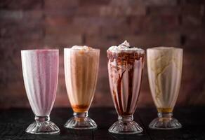 sortiert schüttelt von Banane, Erdbeere, Sahne und Schokolade serviert im Glas isoliert auf hölzern Tabelle Seite Aussicht von Arabisch trinken foto