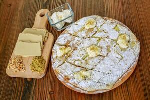 halawa Kuchen mit Sahne mit Pistazie und Walnüsse serviert im hölzern Tafel isoliert auf Tabelle Seite Aussicht von Arabisch Essen foto