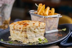 Croque Monsieur oder Schinken und Käse Sandwich mit Französisch Fritten Eimer serviert auf hölzern Tafel isoliert auf Tabelle oben Aussicht von Arabisch Fast Food foto