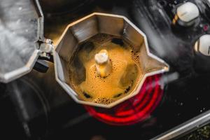 Italienische Aluminium-Kaffeemaschine, die einen frischen dunklen Kaffee auf dem Herd brüht
