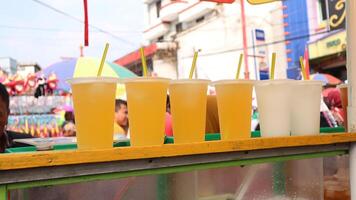 ordentlich Anordnung von vereist Tee und Orange Saft im ein Tasse verkauft auf das Seite von das Straße. foto