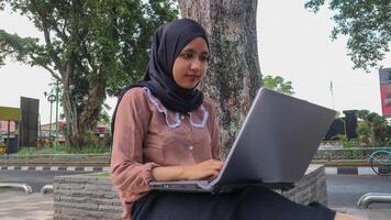 Porträt von arabisch Geschäft Frauen Arbeiten auf Laptop Sitzung beim Stadt Park. foto