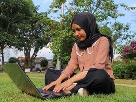 Porträt von arabisch Geschäft Frauen Arbeiten auf Laptop Sitzung beim Stadt Park. foto