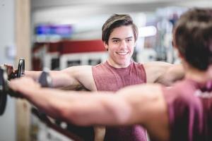 muskulöser gutaussehender Mann mit Hanteln im Fitnessstudio foto