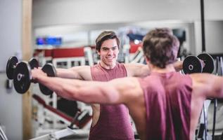 muskulöser gutaussehender Mann mit Hanteln im Fitnessstudio foto