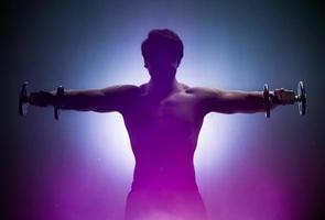 Sportler trainieren Schultern in hellem Licht foto