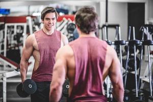 muskulöser gutaussehender Mann mit Hanteln im Fitnessstudio foto