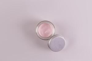 oben Aussicht von ein öffnen Krug von ein kosmetisch Produkt mit ein zart Rosa Textur zum täglich Gesicht und Körper Haut Pflege. Spa. Massage. grau Hintergrund foto