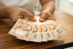 asiatisch Geschäft Frau halten thailändisch Banknote Währung Geld. foto
