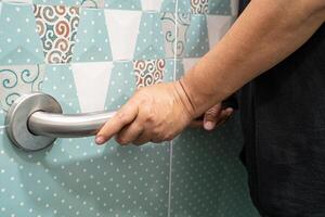 asiatisch Alten Frau verwenden Toilette Badezimmer Griff Sicherheit, gesund stark medizinisch Konzept. foto