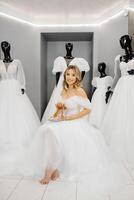 das zukünftige Braut ist tragen ein Hochzeit Kleid beim ein passend zu im das Salon, wählen Schuhe zum das Hochzeit foto