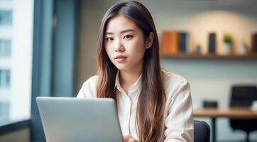 asiatisch Frau Sitzung Arbeiten mit Laptop im modern Büro. modern Frau Arbeiten glücklich foto