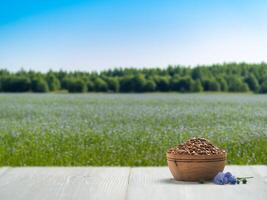 Flachs Saat auf Weiß hölzern Tischplatte Über verschwommen blühen Feld mit Flachs. Leinsamen Öl spotten oben mit Kopieren Raum. foto