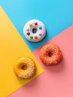 kreativ Layout gemacht von köstlich glasiert Donuts. Vertikale eben legen - - Donuts oder Donuts auf bunt Hintergrund mit Kopieren Raum. Blau, Gelb und Rosa geometrisch Hintergrund. foto