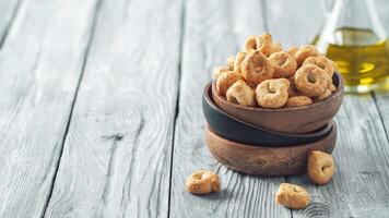 traditionell Italienisch Snack Taralli oder Tarallini im hölzern Schüssel Über alt grau hölzern Tisch. rustikal Schuss von Taralli Vorspeise mit Kopieren Raum. horizontal Banner foto