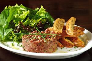 Steak Tartar mit Blatt Salat und rustikal Kartoffeln foto