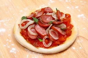 Mini Pizza mit Tomate Soße, Würstchen und Zwiebeln foto