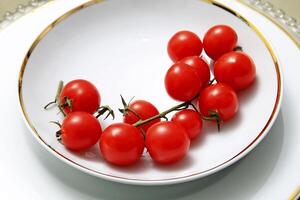 Teller mit Tomaten auf Tabelle mit Panettone, Gläser, Obst und Wein foto