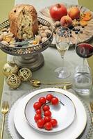 Teller mit Tomaten auf Tabelle mit Panettone, Gläser, Obst und Wein foto