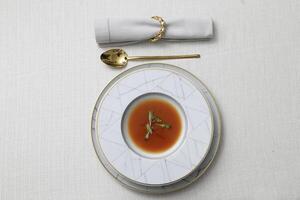 Teller mit Gazpacho und golden Besteck auf das Tabelle foto