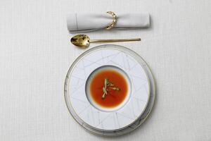 Teller mit Gazpacho und golden Besteck auf das Tabelle foto