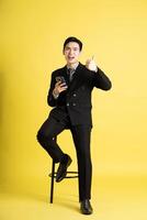 Porträt von asiatisch männlich Geschäftsmann. tragen ein passen und posieren auf ein Gelb Hintergrund foto