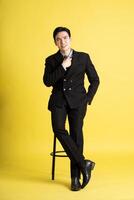 Porträt von asiatisch männlich Geschäftsmann. tragen ein passen und posieren auf ein Gelb Hintergrund foto