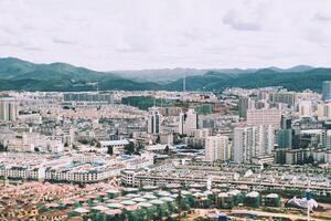 Yunan, China, 2016 - - Antenne fotografieren von ein Metropole' Gebäude mit Wolke beim das Blau Himmel im Hintergrund. Dort wurden Berge alle um das Stadt. foto