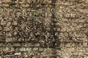 Stein Textur von ein Mauer im Montenegro. uralt Mauer zusammengesetzt von braun farbig Steine. nass Schweiß von Wasser ist bedeckt mit Schimmel. Hintergrund. Vorlage. zum Design. horizontal. foto