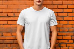 jung Mann tragen leer Weiß T-Shirt im Vorderseite von das Backstein Mauer. Attrappe, Lehrmodell, Simulation T-Shirt Vorlage. foto