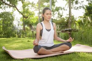 jung Frau im Sportbekleidung tun Meditation trainieren und Yoga draussen, gesund Lebensstil, mental Gesundheit Konzept. foto