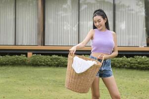 jung asiatisch Frau halten Wäsche Korb im Hinterhof draussen foto