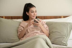 jung asiatisch Frau mit Clever Telefon Lügen auf Bett foto