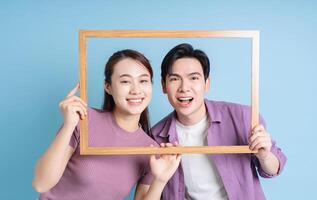 jung asiatisch Paar halten Foto Rahmen auf Blau Hintergrund