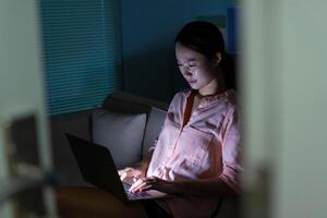 Foto von jung asiatisch Frau mit Laptop im das dunkel beim Mitternacht