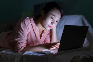 Foto von jung asiatisch Frau mit Laptop im das dunkel beim Mitternacht