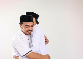 zwei jung indonesisch Muslim männlich Umarmung und lächelnd während eid al fitr festlich foto