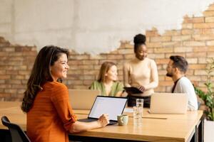 Geschäft Frau Arbeiten auf Laptop mit ihr jung multiethnisch Anfang Mannschaft im das modern Büro foto