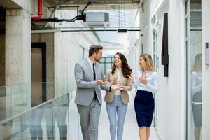 jung Anfang Mannschaft haben ein Diskussion während Gehen im das modern Büro Gang foto