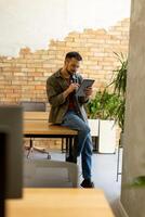 lächelnd Mann mit Tablette im ein modern gemauert Büro foto