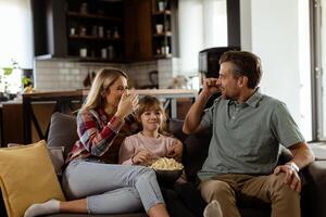 gemütlich Familie Zeit, Teilen Lachen und Popcorn auf ein beiläufig Abend foto