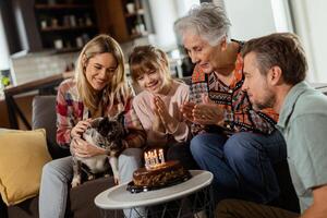 freudig Familie feiern Großmütter Geburtstag mit Kuchen im ein gemütlich Leben Zimmer foto