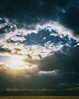 das Sonne brechen durch Sturm Wolken im ein blühen Raps Feld. Ästhetik von Jahrgang Film. foto