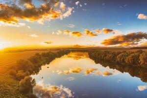 ein Sonnenuntergang oder Sonnenaufgang Szene Über ein See oder Fluss mit wolkig Himmel reflektieren im das Wasser auf ein Sommer- Abend oder Morgen. Ästhetik von Jahrgang Film. foto