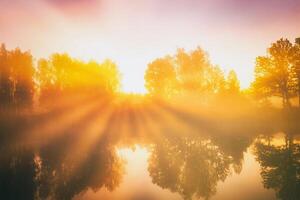 Dämmerung auf ein See oder Fluss mit ein Himmel reflektiert im das Wasser, Birke Bäume auf das Ufer und das Sonnenstrahlen brechen durch Sie und Nebel im Herbst. Ästhetik von Jahrgang Film. foto