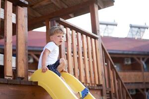 wenig Junge rutschen spielen Spielplatz aktiv Kindheit genießen Sommer- foto