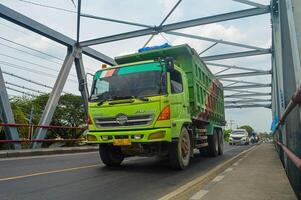 ein Hino Dump LKW ist Vorbeigehen auf ein Stahl Fachwerk Brücke, Indonesien, 16 Januar 2024. foto