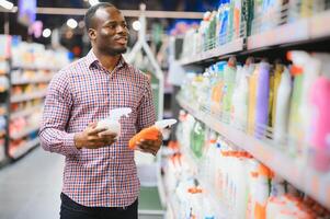 afrikanisch Mann halten Flasche von Haushalt Chemikalien im groß Geschäft foto
